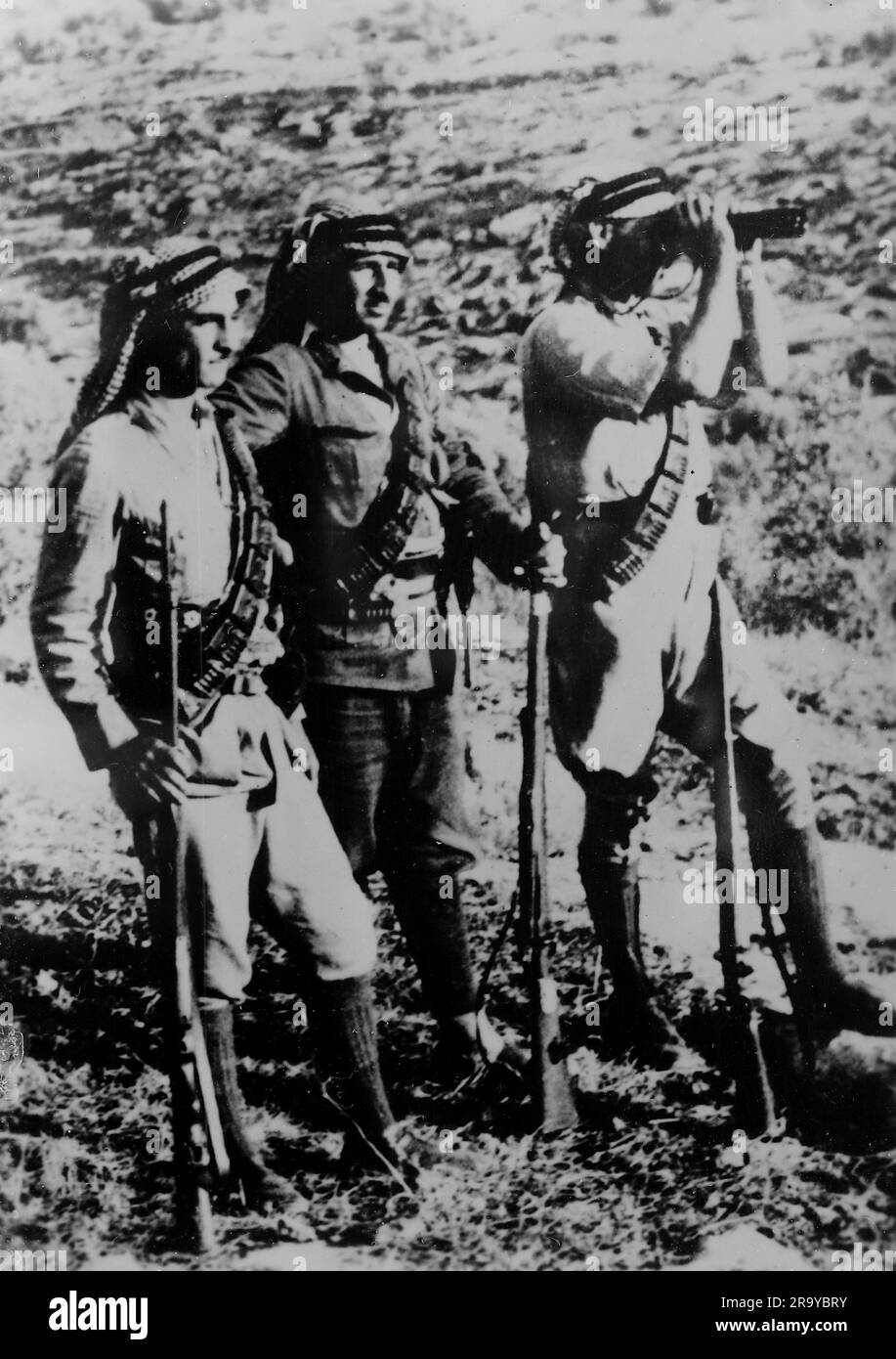 Un gruppo di tre arabi armati, uno che guarda attraverso un binocolo, parte di un gruppo descritto come "briganti" (un membro di una banda che imboscava e derubava le persone nelle foreste e nelle montagne). Questa fotografia è tratta da un album fotografico di fotografie, c1937, durante l'occupazione della Palestina da parte dell'esercito britannico. La Gran Bretagna amministrò la Palestina per conto della società delle Nazioni tra il 1920 e il 1948, un periodo denominato "mandato britannico”. Foto Stock