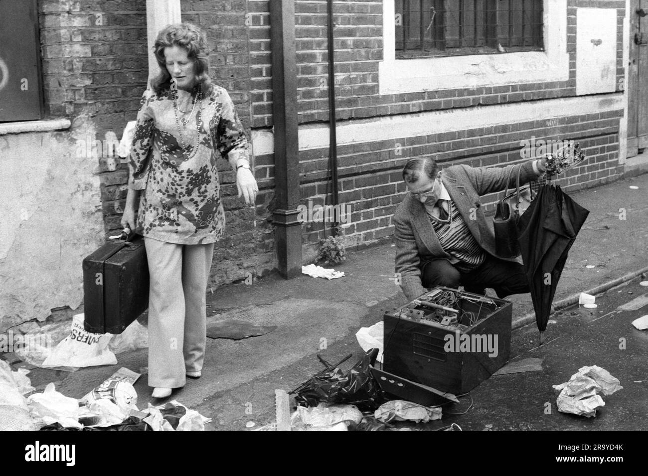 1970s East End Londra, Brick Lane. Un uomo che cerca parti radio a transistor e una donna ben vestita con una valigia che ha appena trovato alla fine del mercato domenicale. Tower Hamlets, Londra, Inghilterra circa 1978. 1970 UK HOMER SYKES Foto Stock