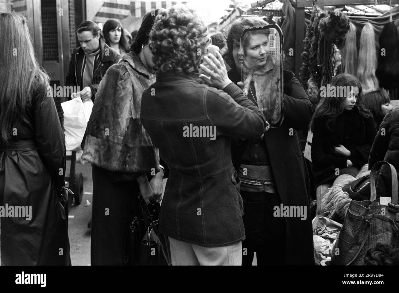 East End London anni '1970, donne che fanno shopping lungo il Roman Road Market, un elegante East Ender prova su una parrucca riccia alla moda, Tower Hamlets, Londra, Inghilterra 1975. 70 UK HOMER SYKES Foto Stock