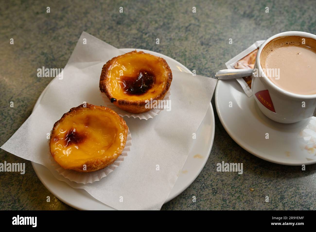 Due tradizionali pasticcini portoghesi con crostata all'uovo, Pastel de nata, con una tazza di caffè Foto Stock