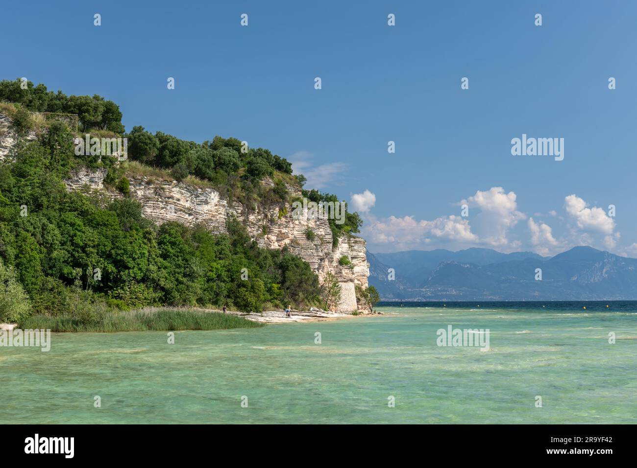 Il bellissimo e pittoresco litorale della penisola di Sirmione. Una spiaggia rocciosa a Sirmione, Lago di Garda, Italia, Europa Foto Stock