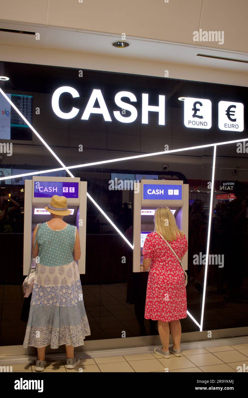 Due viaggiatori utilizzano un bancomat GBP ed Euro all'aeroporto di Londra Luton Foto Stock