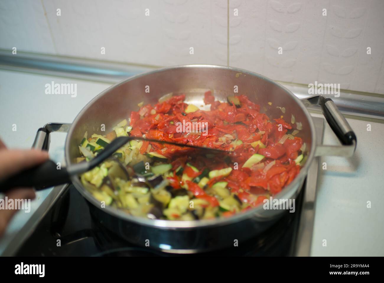 Persona irriconoscibile che cucina verdure. Interni Foto Stock