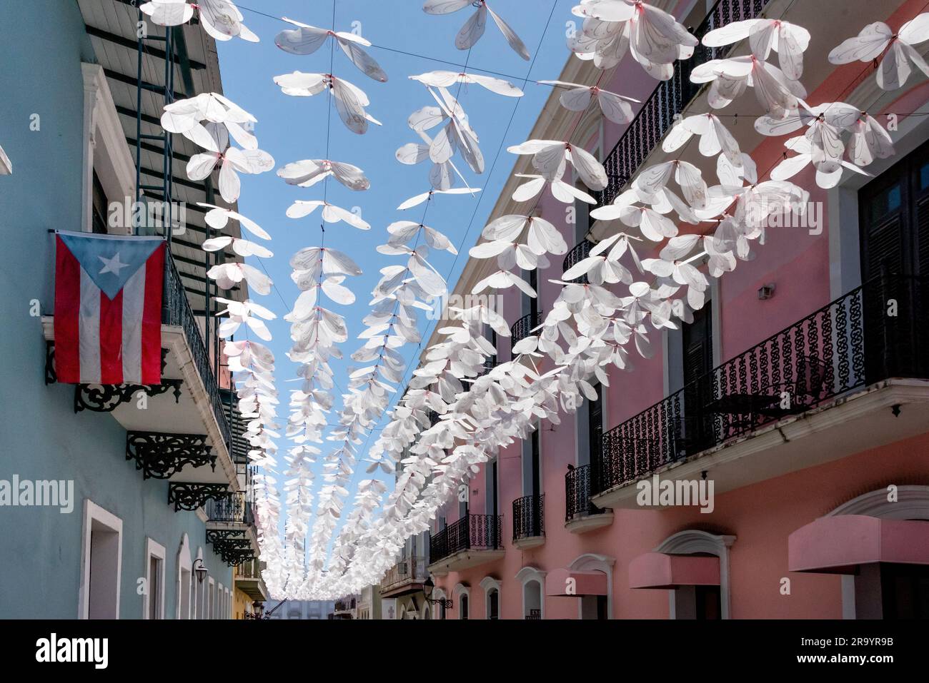 Calle Fortaleza (ex strada degli ombrelli) nella Vecchia San Juan Puerto Rico con rastrellieri di farfalle bianche sopra la testa e bandiera; popolare area turistica per lo shopping Foto Stock