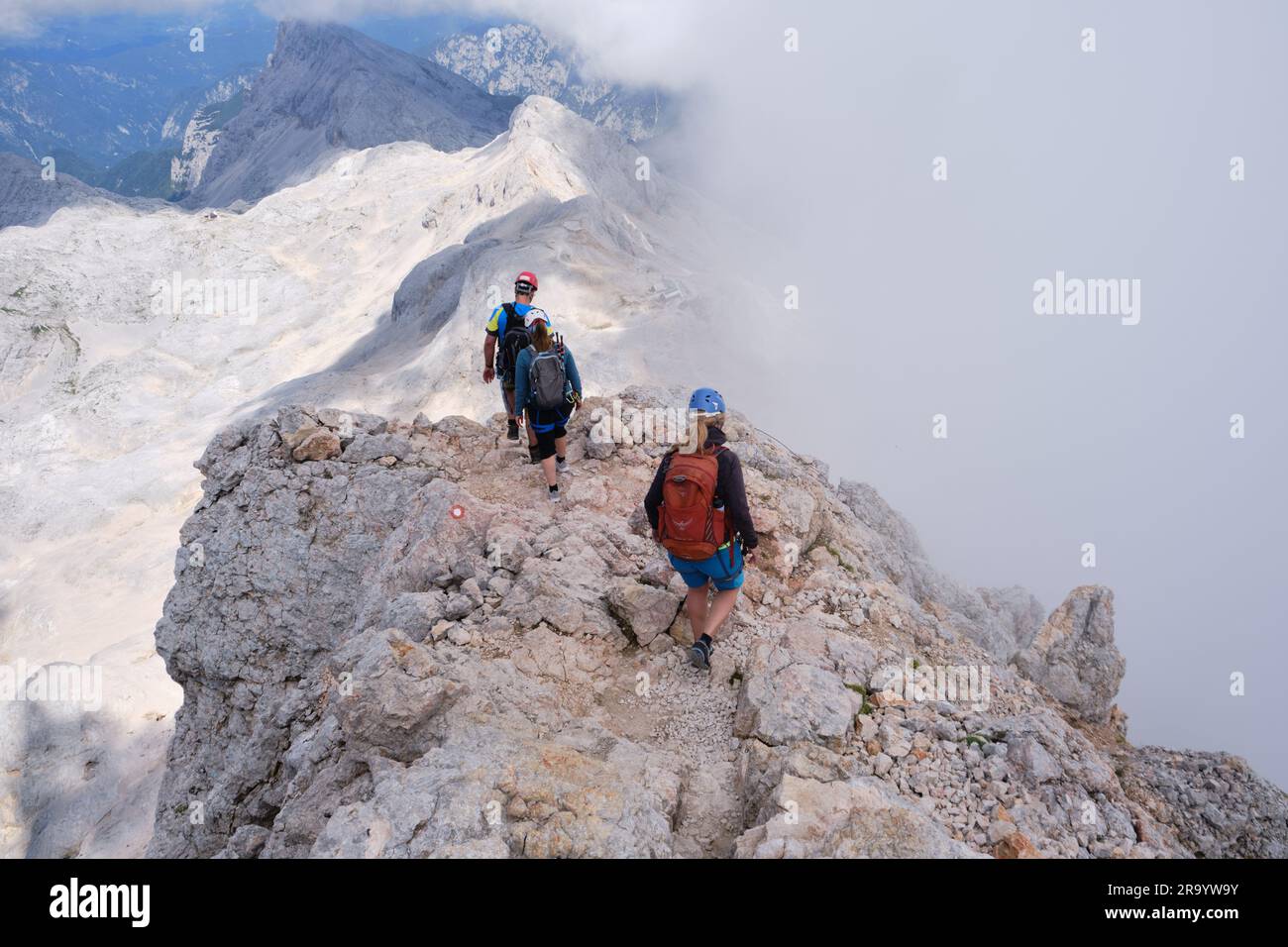 La gente scende dalla vetta del Triglav, su una cresta rocciosa, con nebbia, durante l'estate. Parco nazionale del Triglav, Slovenia - 3 agosto 2022. Foto Stock