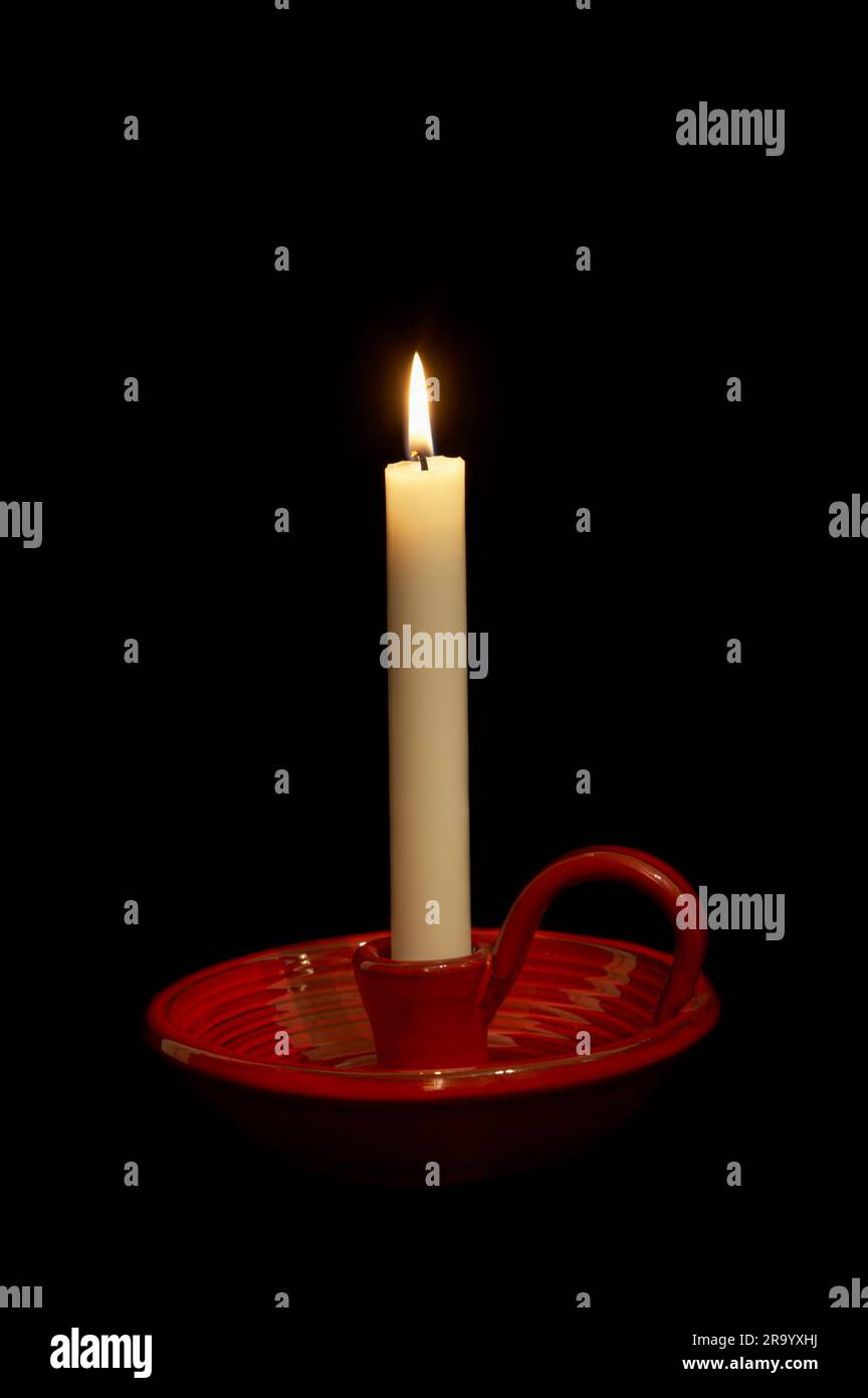 Primo piano della candela accesa in un portacandele in ceramica isolato su sfondo nero Foto Stock