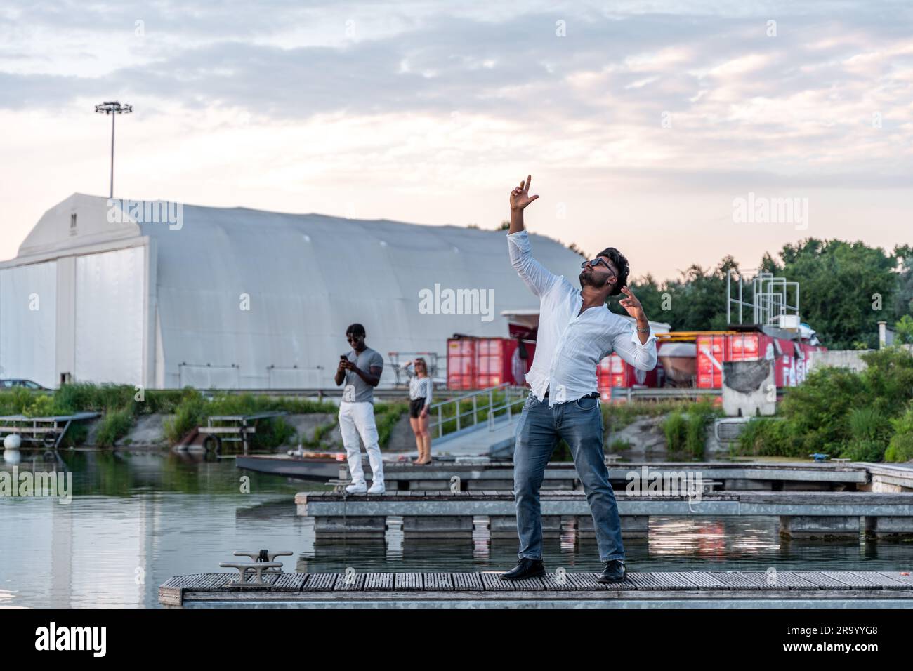 piccolo gruppo di giovani amici multietnici che si divertono sui moli di un porto fluviale - concetto di vacanza estiva Foto Stock