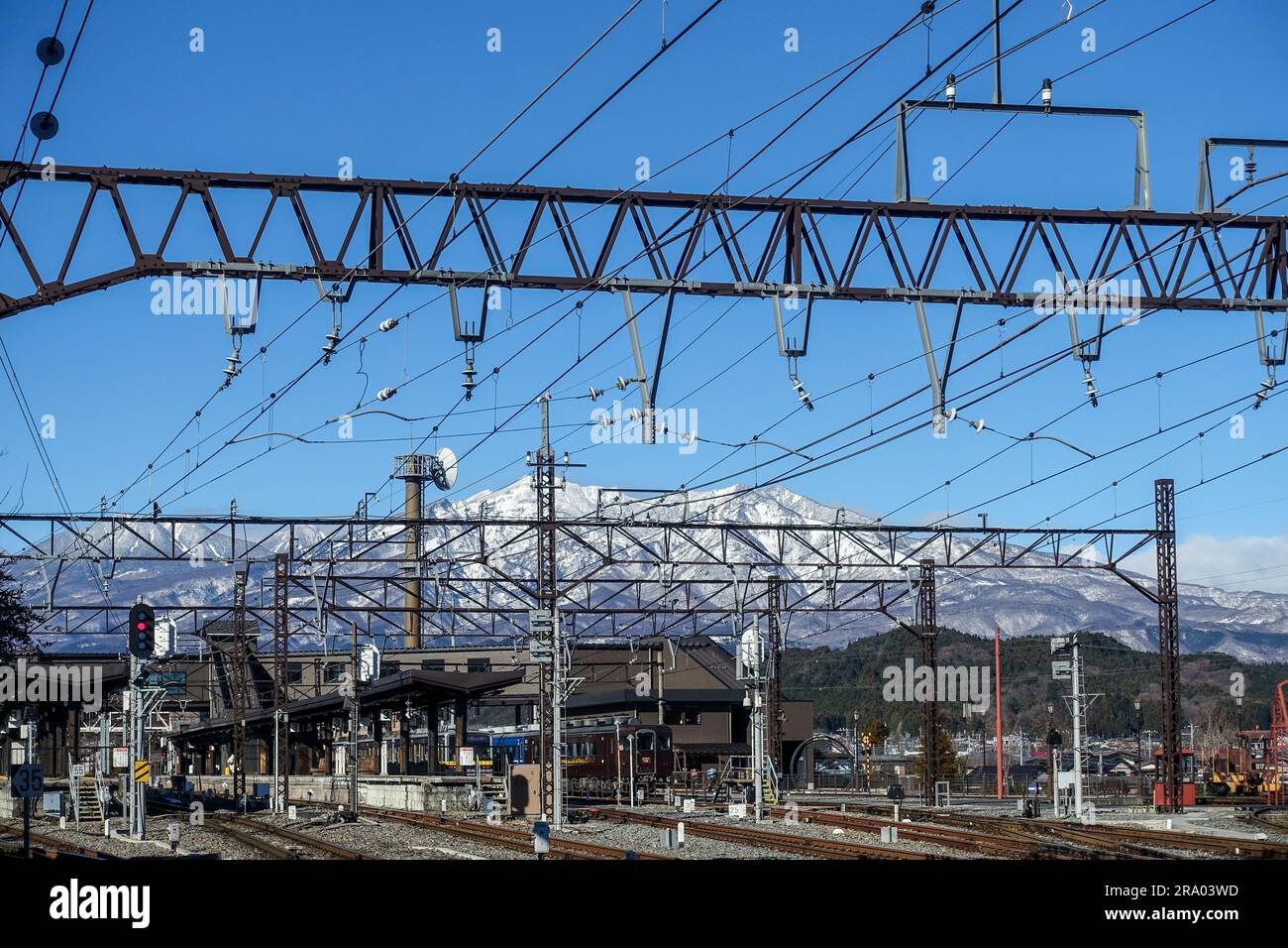 Stazione ferroviaria Nikko, binari, con le Alpi giapponesi innevate nel retroterra Foto Stock