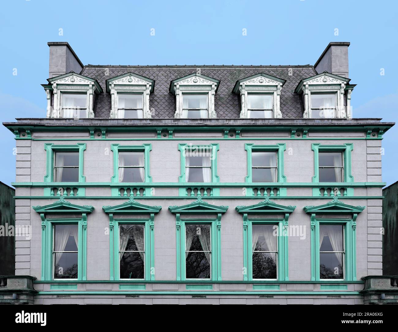 Vecchio edificio di appartamenti con tetto mansarda e cornici ornate intorno alle finestre Foto Stock