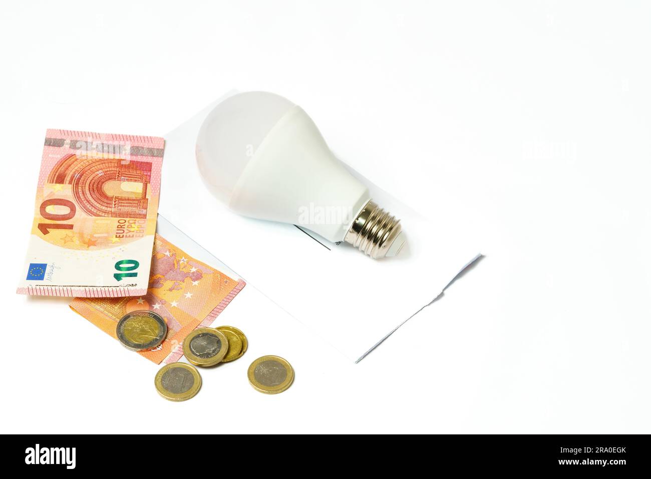 Lampadina su una bolletta elettrica e banconote e monete su sfondo bianco.concetto di aumento del prezzo dell'elettricità Foto Stock