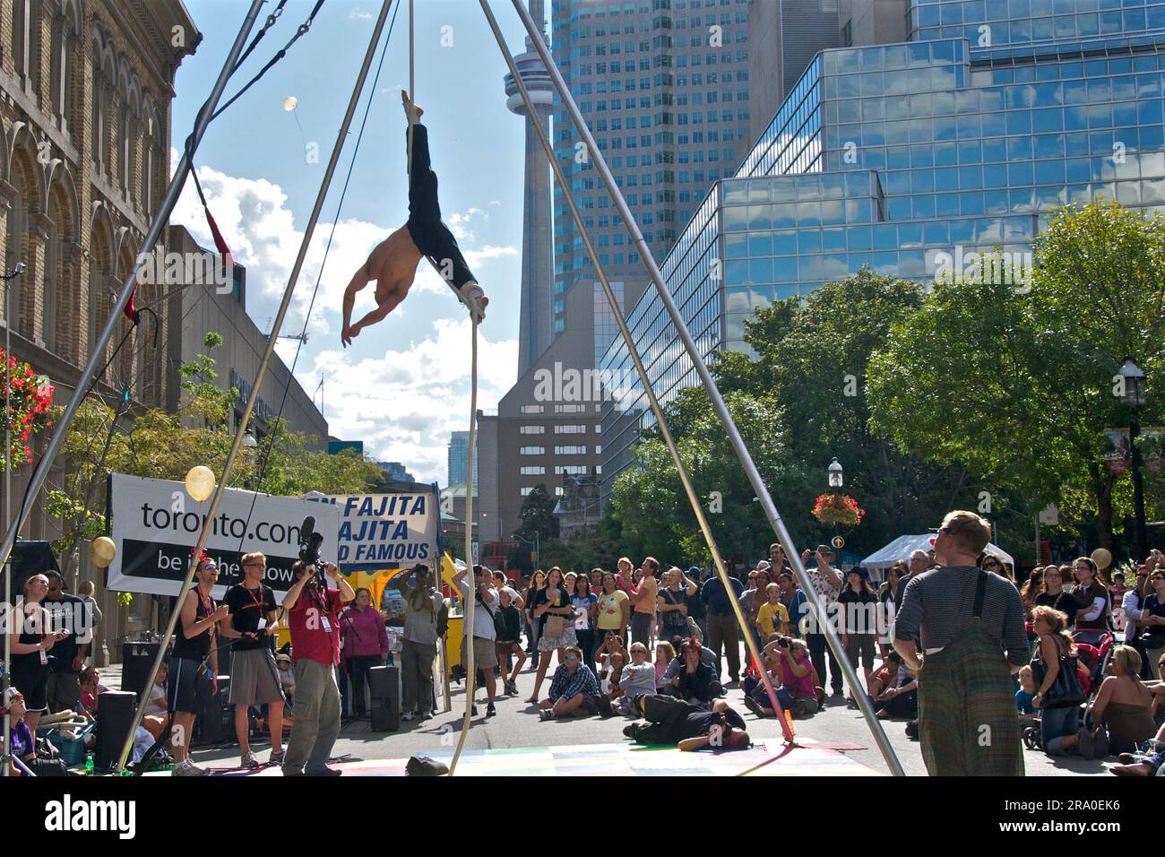 Toronto, Ontario/Canada - 26 agosto 2010: Il fotografo scatta una foto in un angolo basso della ginnasta appesa alla corda in un festival di strada a Toronto Foto Stock