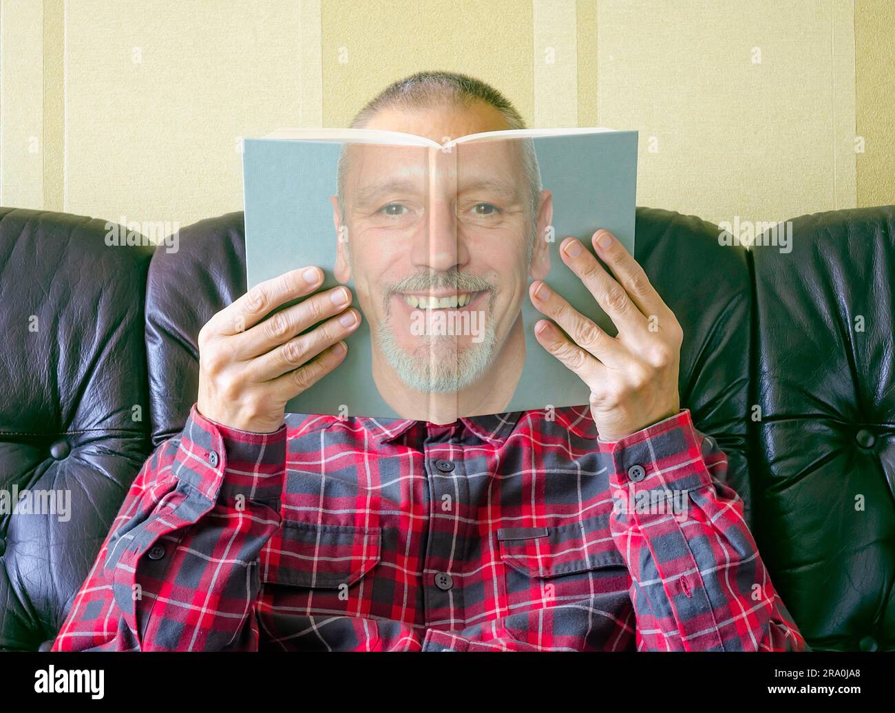 Un uomo che legge un libro su se stesso, con la faccia vista sulla copertina Foto Stock