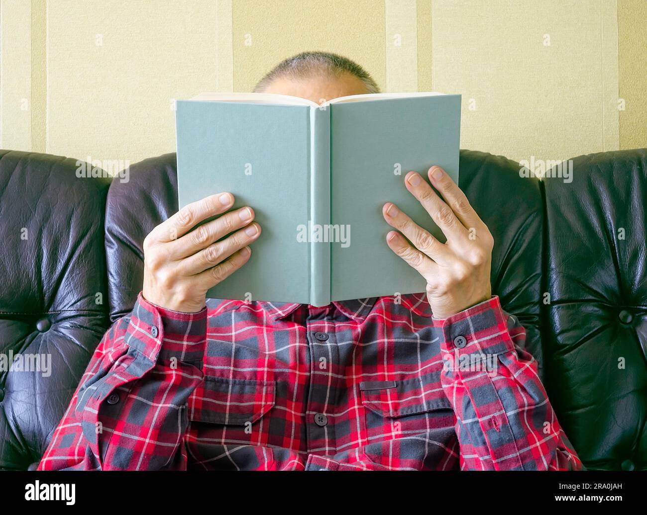 Un uomo di lettura, con il volto coperto dal libro Foto Stock