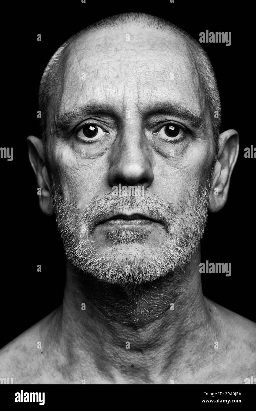 Drammatico ritratto in bianco e nero di un uomo adulto con una triste espressione su sfondo nero Foto Stock
