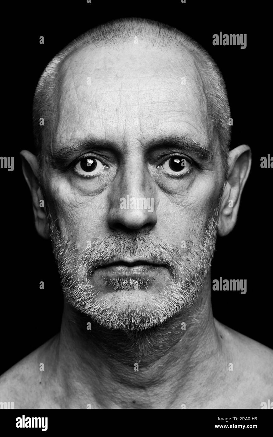 Drammatico ritratto in bianco e nero di un uomo adulto con una triste espressione su sfondo nero Foto Stock