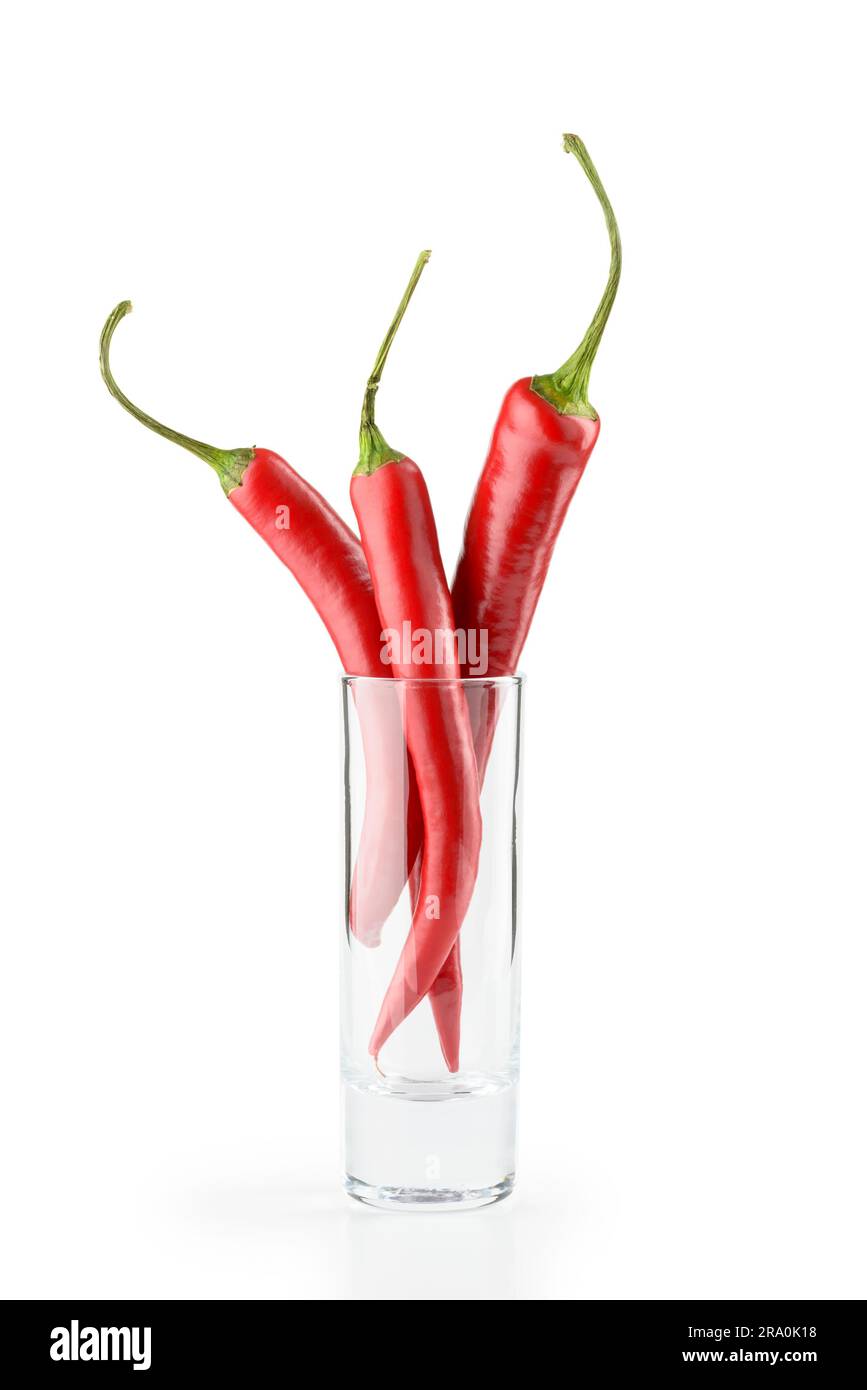 Tre red hot chili peppers in un bicchiere di vodka, isolato su sfondo bianco Foto Stock
