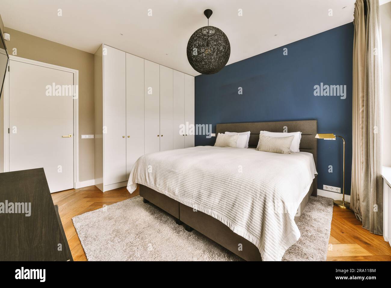 una camera da letto con pareti blu e mobili bianchi sul pavimento, insieme  ad un grande letto di fronte ad essa Foto stock - Alamy