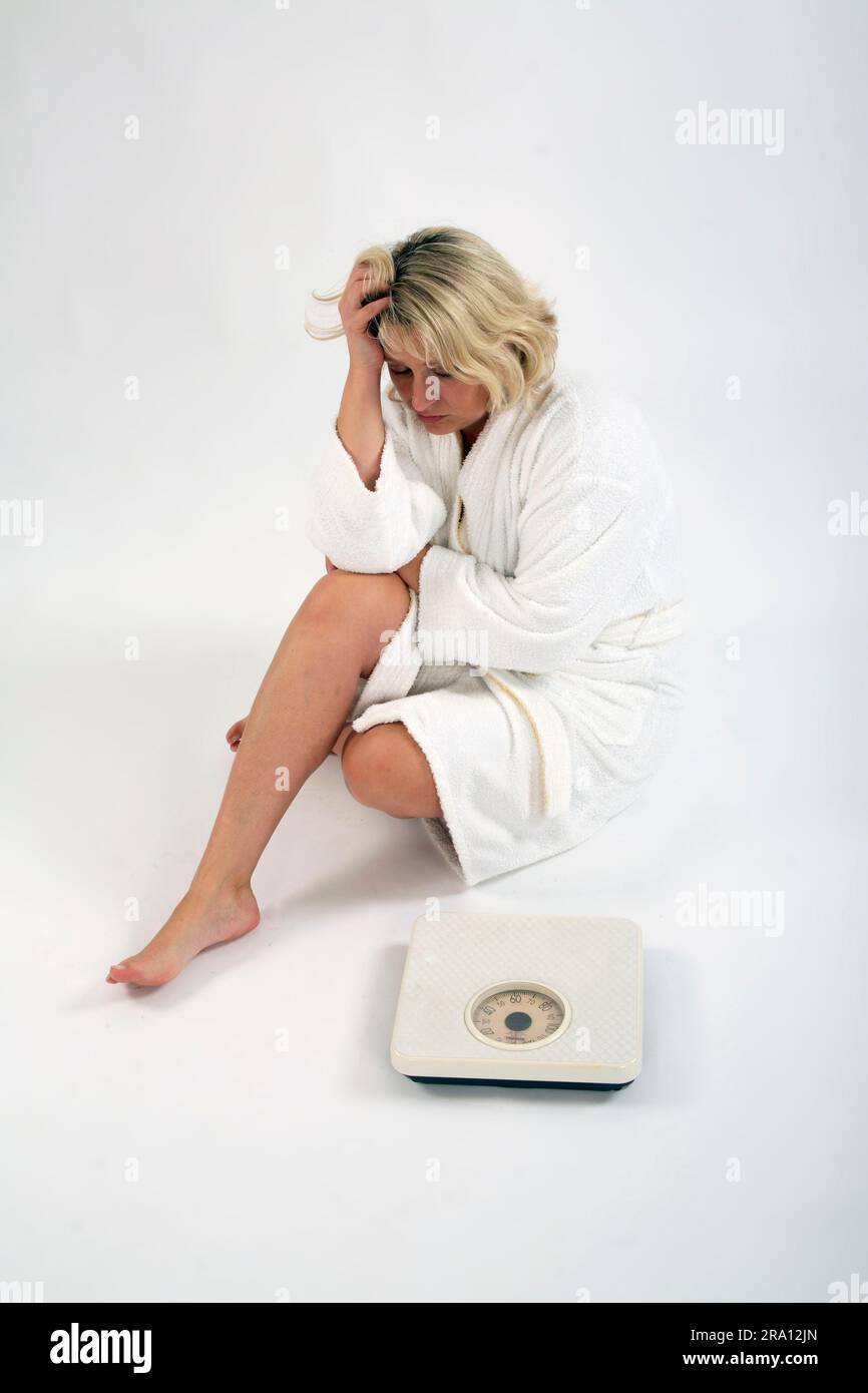 Donna disperata seduta accanto alla bilancia, bilancia del bagno, ritaglio, oggetto Foto Stock