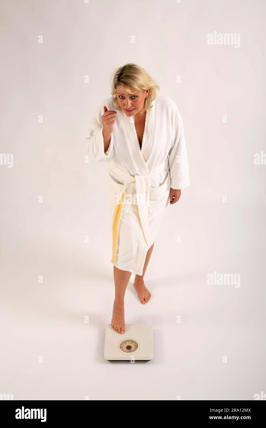 La donna in accappatoio non osa salire su bilance, peso, bilance da bagno, esemplare, oggetto, esitate Foto Stock