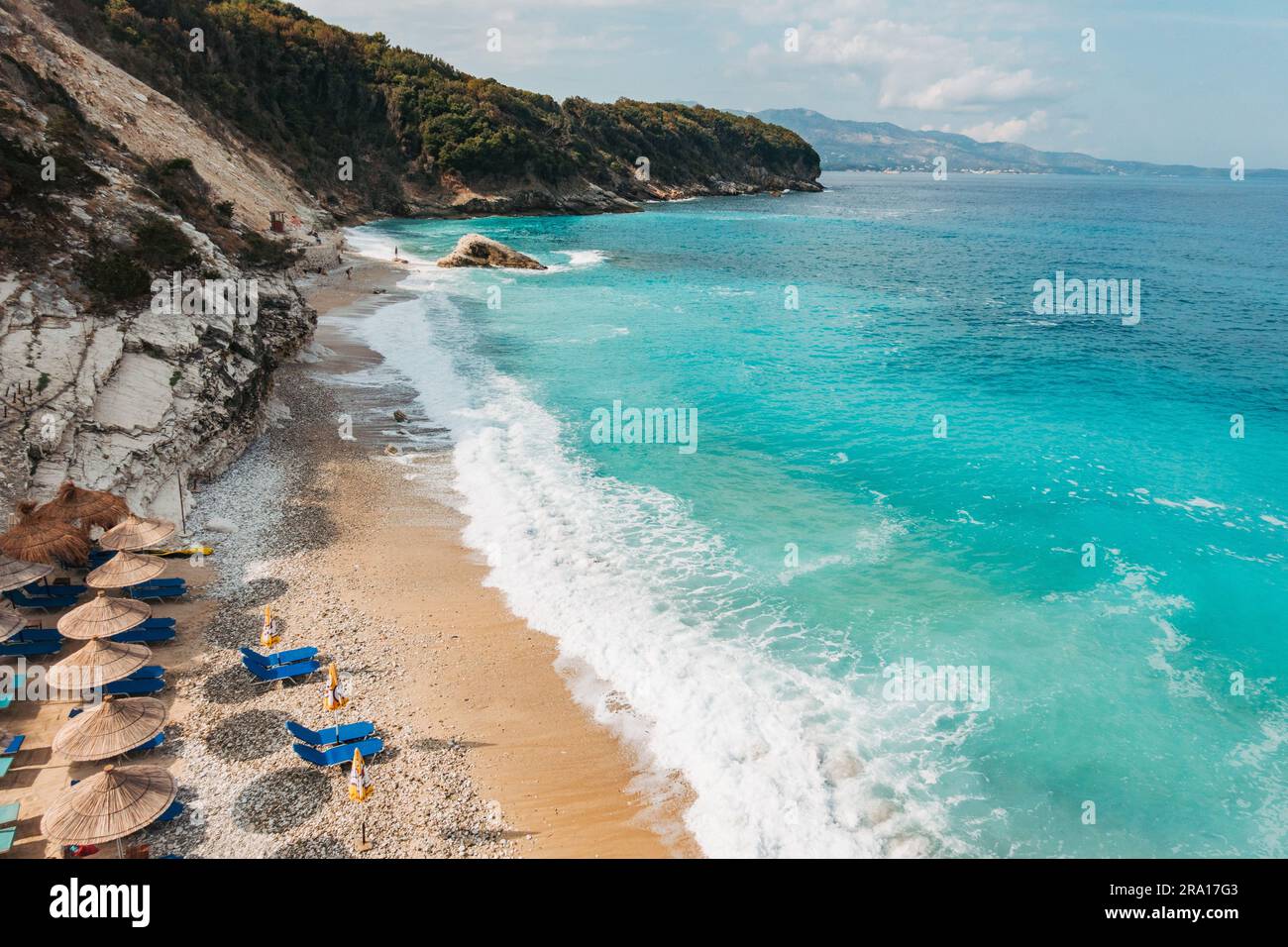 Lettini e ombrelloni pronti per i turisti sulle rive turchesi della spiaggia di Pulëbardha a Ksamil, Albania Foto Stock