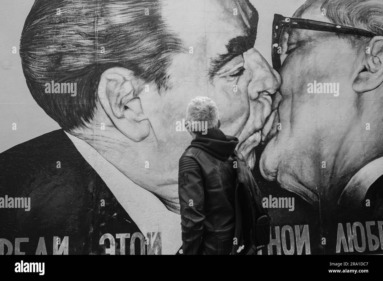 Berlino, Germania - 19 aprile 2023: Veduta di un turista che guarda il muro di Berlino in Germania, mostrando Leonid Brezhnev ed Erich Honecker in una fraterna Foto Stock