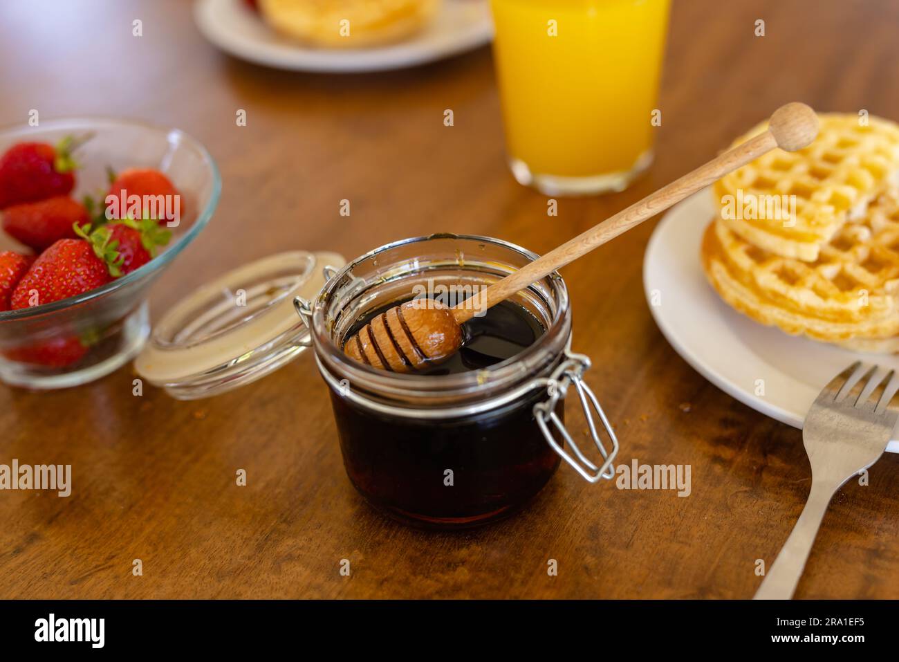 Primo piano su un tavolo di legno con fragole, marmellata, waffle e succo di frutta Foto Stock
