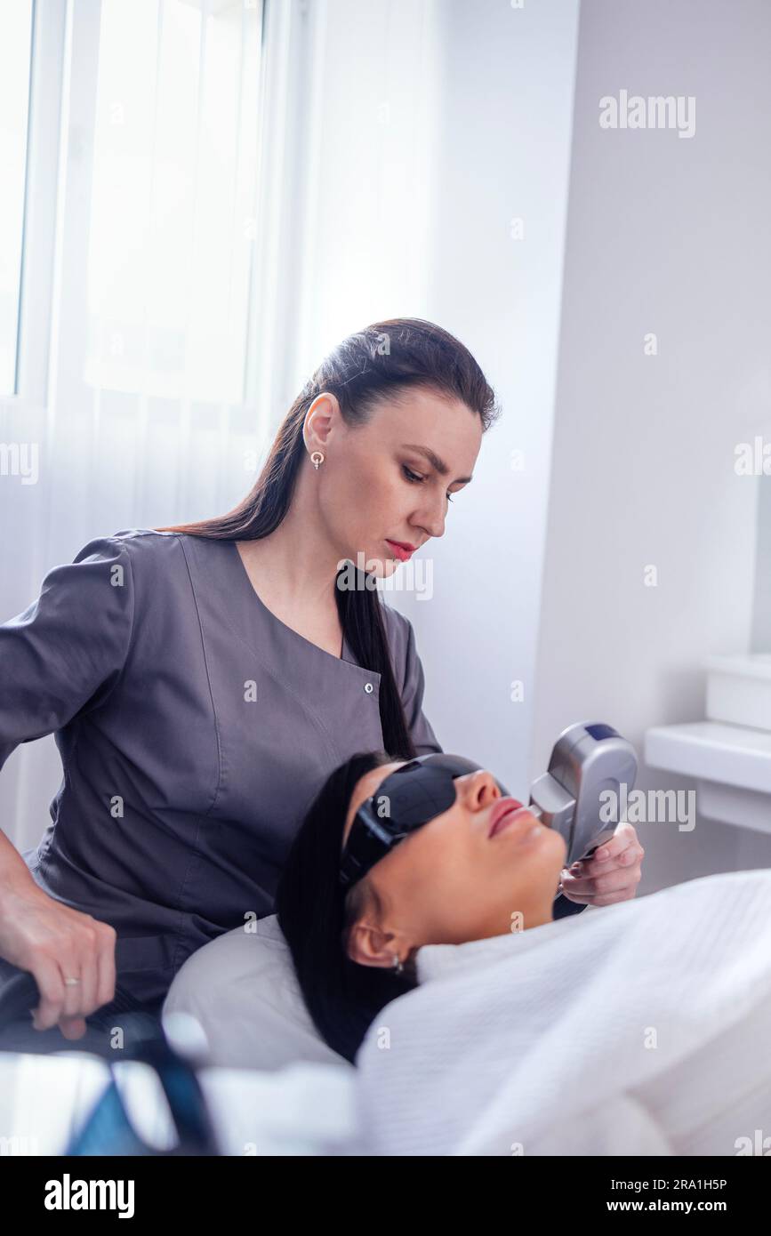 Ritratto di giovane donna rilassato ottenere SMAS ultrasuoni viso sollevamento massaggio con attrezzature professionali in centro di bellezza Foto Stock