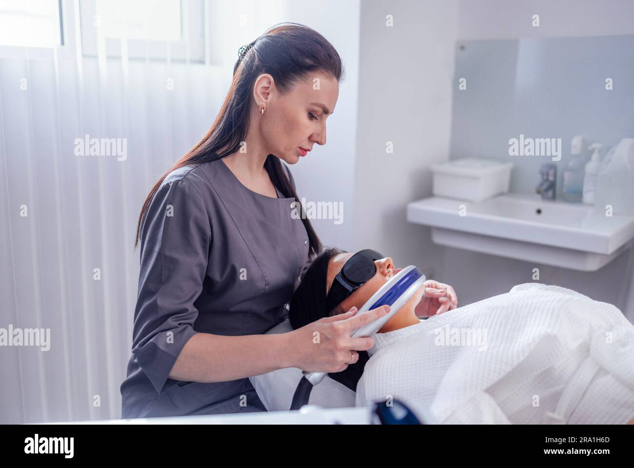 Ritratto di giovane donna rilassato ottenere SMAS ultrasuoni viso sollevamento massaggio con attrezzature professionali in centro di bellezza Foto Stock