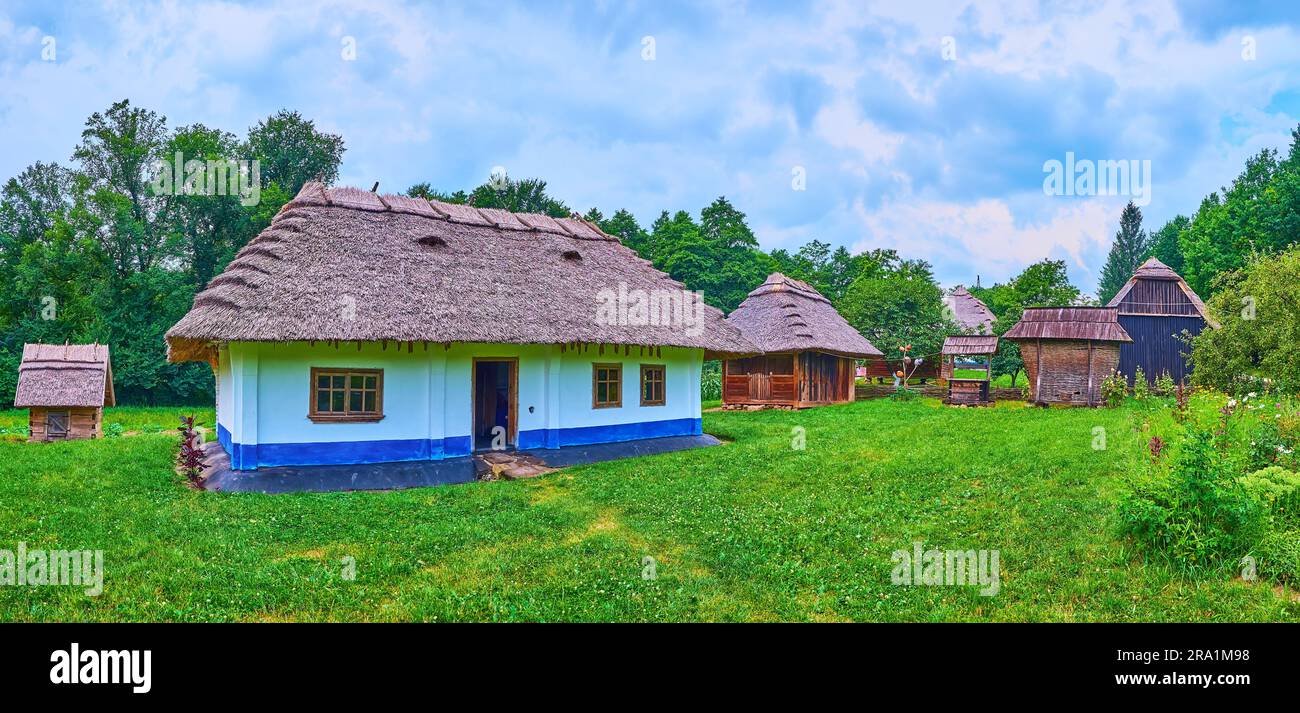 La vecchia fattoria del villaggio con casa hata bianco-blu, fienili di legno e un grande giardino verde, Chernivtsi scansen, Ucraina Foto Stock