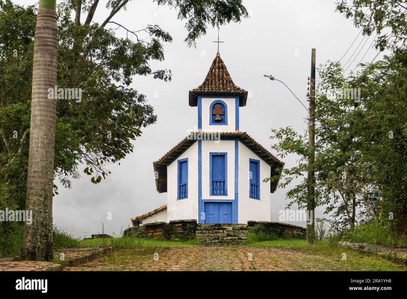 Cappella coloniale incorniciata da alberi e fondali nebbiosi, Catas Altas, Minas Gerais, Brasile Foto Stock