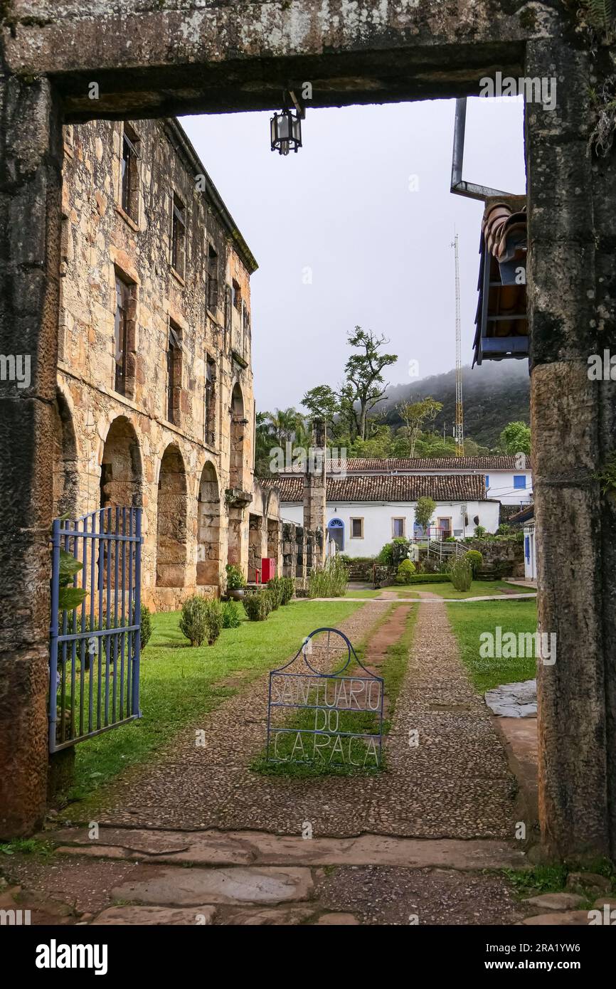 Ammira attraverso un cancello d'ingresso stoney lo storico museo restaurato del Santuario di Caraca con archi e finestre, Minas Gerais, Brasile Foto Stock