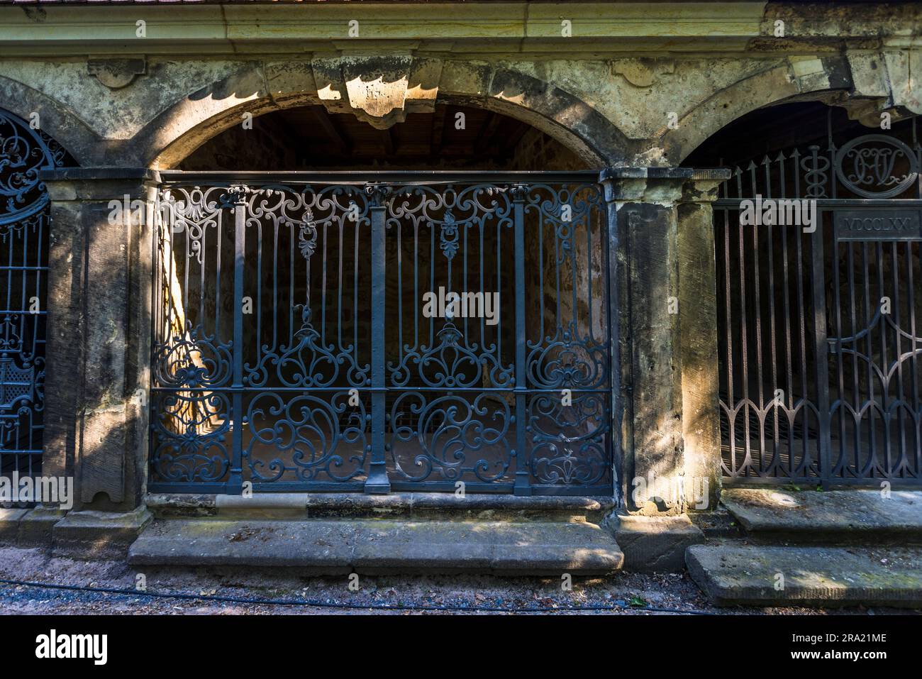 Un intricato lavoro di grata in ferro battuto chiude l'ingresso di una casa cripta al cimitero di Elias a Dresda, Sassonia, Germania. Una lastra di pietra accanto al cancello porta un anno a malapena leggibile in numeri romani. Qui erano impilati bare nelle camere sepolcrali murate che, a differenza delle tombe in terra, causavano una notevole molestia olfattiva. Approntato nel 1680 come cimitero della peste, il cimitero di Elias fu notevolmente ampliato e murato nel 1724 sotto la direzione dei maestri costruttori George Bähr, architetto della Frauenkirche di Dresda, e Johann Gottfried Fehre, che aggiunse 41 case cripta a volta (Grufthäuser) con fronti ad arco Foto Stock