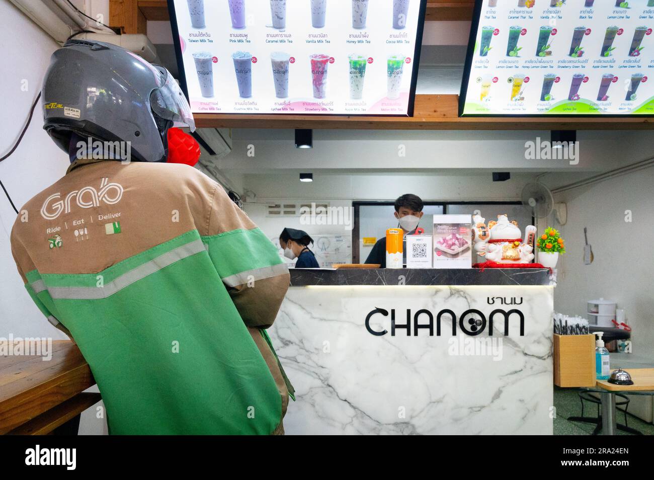 Prendi il cibo che ti consegnerà l'autista del ciclomotore aspetta per l'ordine al Bubble Tea Cafe, Bangkok, Thailandia Foto Stock