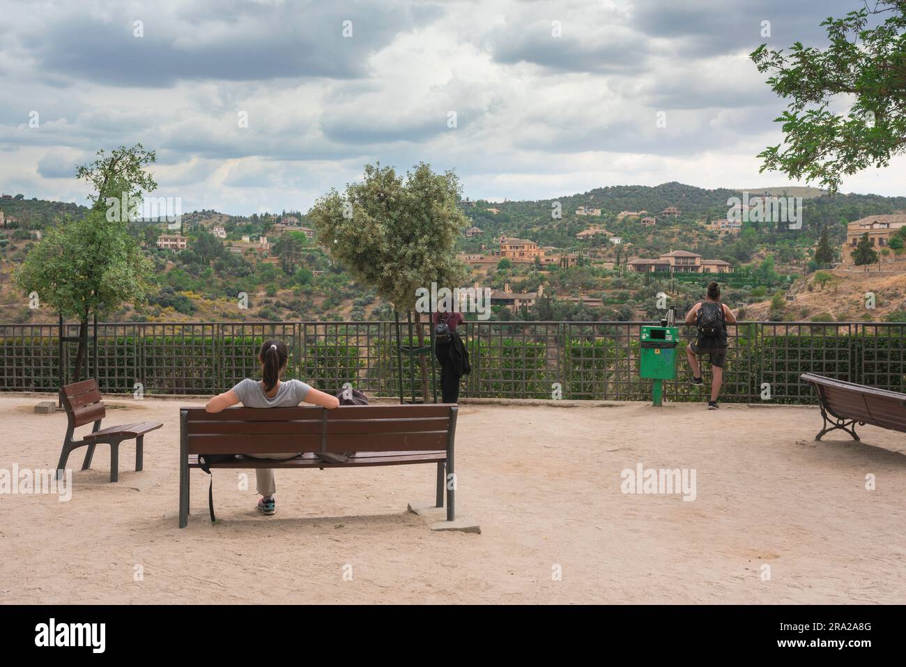 Donna single Travel, vista posteriore di una giovane donna seduta da sola su una panchina e guardando un punto panoramico, la Spagna, l'Europa Foto Stock