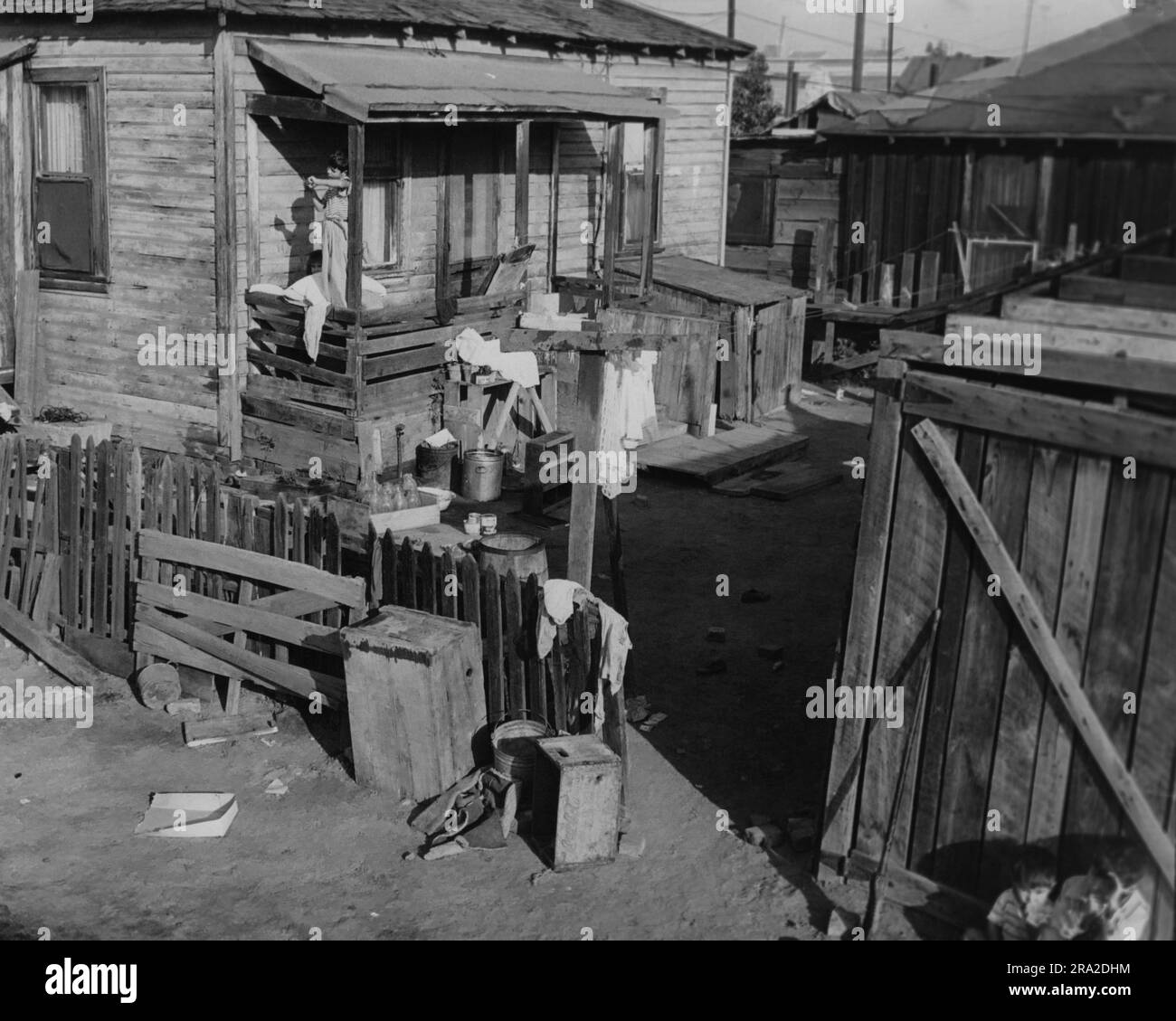 La scena di una casa in un quartiere povero. Ragazza con un vestito in piedi sul portico posteriore Foto Stock