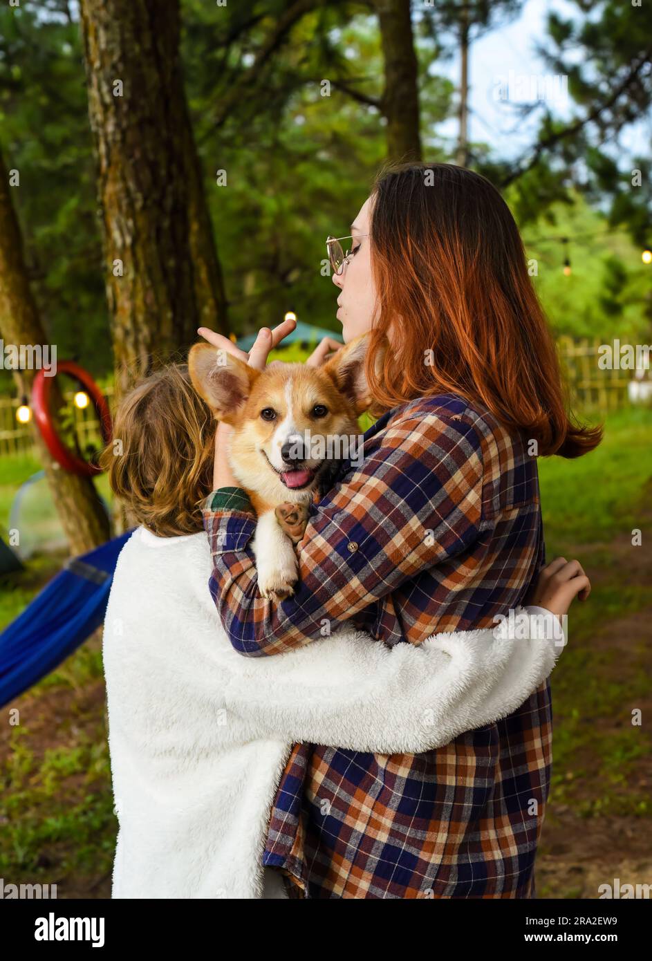 Sorelle accoglienti che tengono in mano il loro sorridente cane corgi gallese Foto Stock