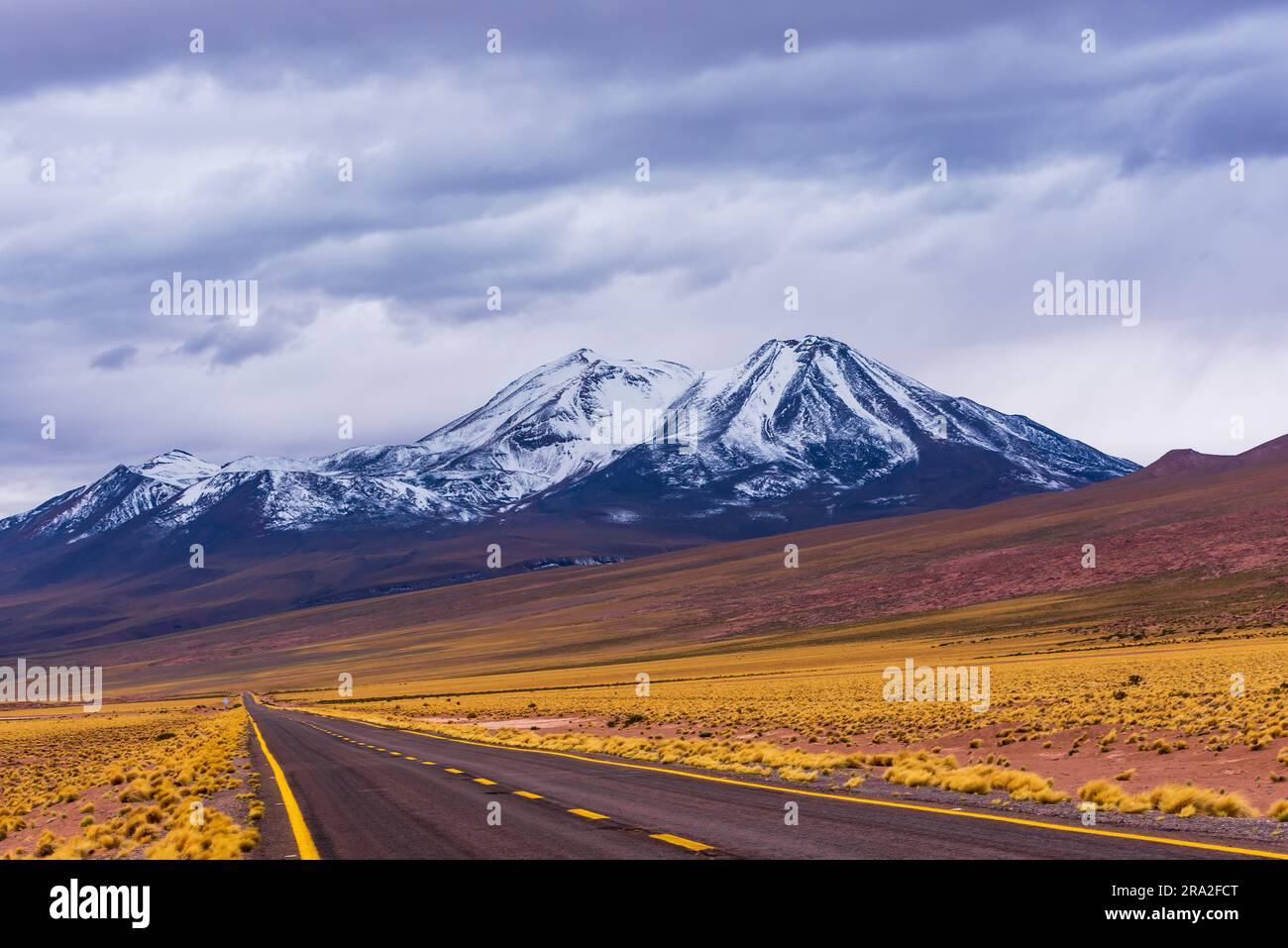 Strada infinita verso il picco vulcanico innevato nel deserto di Atacama Foto Stock