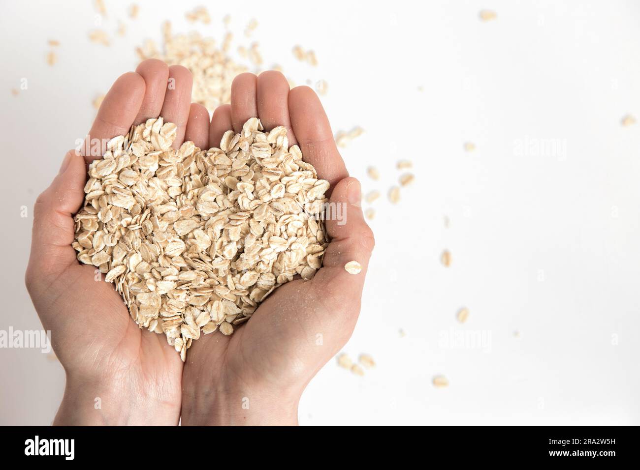 Mani piene che formano un cuore con fiocchi d'avena su sfondo bianco, immagine concettuale. Alimenti super ricchi di sostanze nutritive che possono essere utilizzati per diverse ricette Foto Stock Mani piene che formano un cuore con fiocchi d'avena su sfondo bianco, immagine concettuale. Alimenti super ricchi di sostanze nutritive che possono essere utilizzati per diverse ricette Foto Stock
