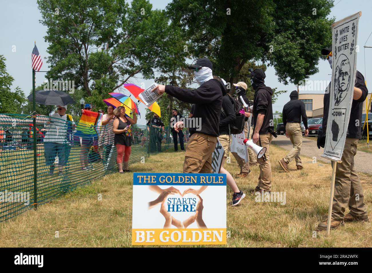 HUDSON, WISCONSIN, USA - 17 GIUGNO 2023: Manifestanti anti anti LGBTQ+ non identificati mascherati e partecipanti al festival alla celebrazione dell'Hudson Pride. Foto Stock