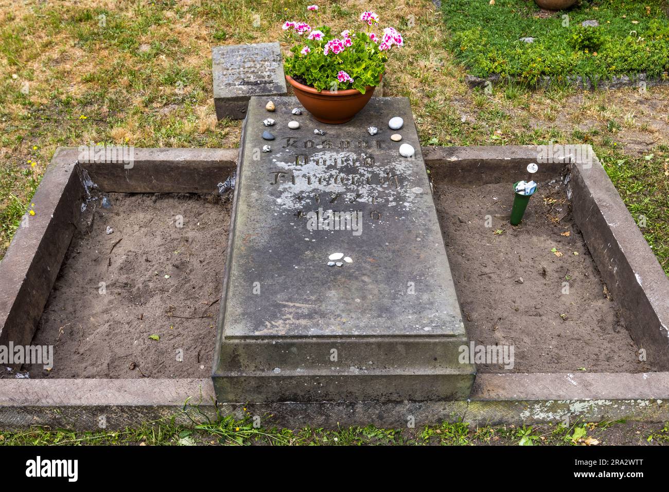 Una lapide piatta con l'iscrizione parzialmente erosa "Kaspar David Friedrich" segna il luogo di riposo finale del pittore nel cimitero di Trinitatis a Dresda, Sassonia, Germania, decorato con un vaso di gerani e piccoli ciottoli lasciati come segno di ricordo. Friedrich, nato a Greifswald nel 1774, morì impoverito e largamente dimenticato a Dresda nel 1840 – solo postumo fu riconosciuto come il più importante pittore del romanticismo tedesco. Il cimitero di Trinitatis fu progettato nel 1815/16. Foto Stock
