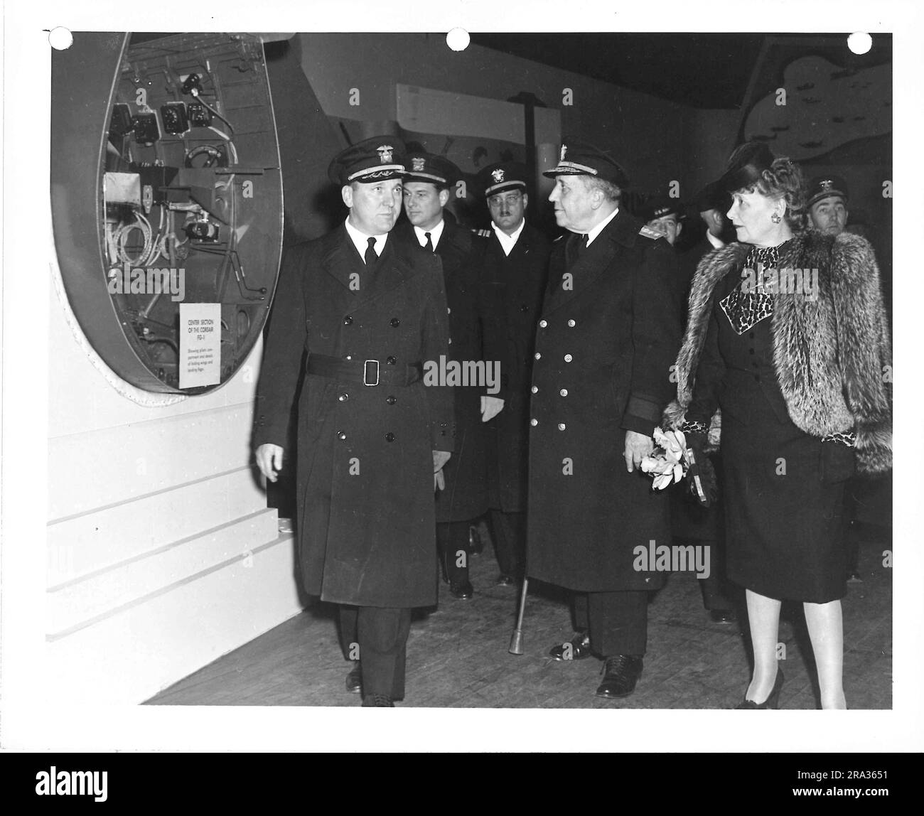 Foto di uomini in uniforme militare e donne in camice di pelliccia che escono dalla mostra Corsair FG-1. Foto Stock