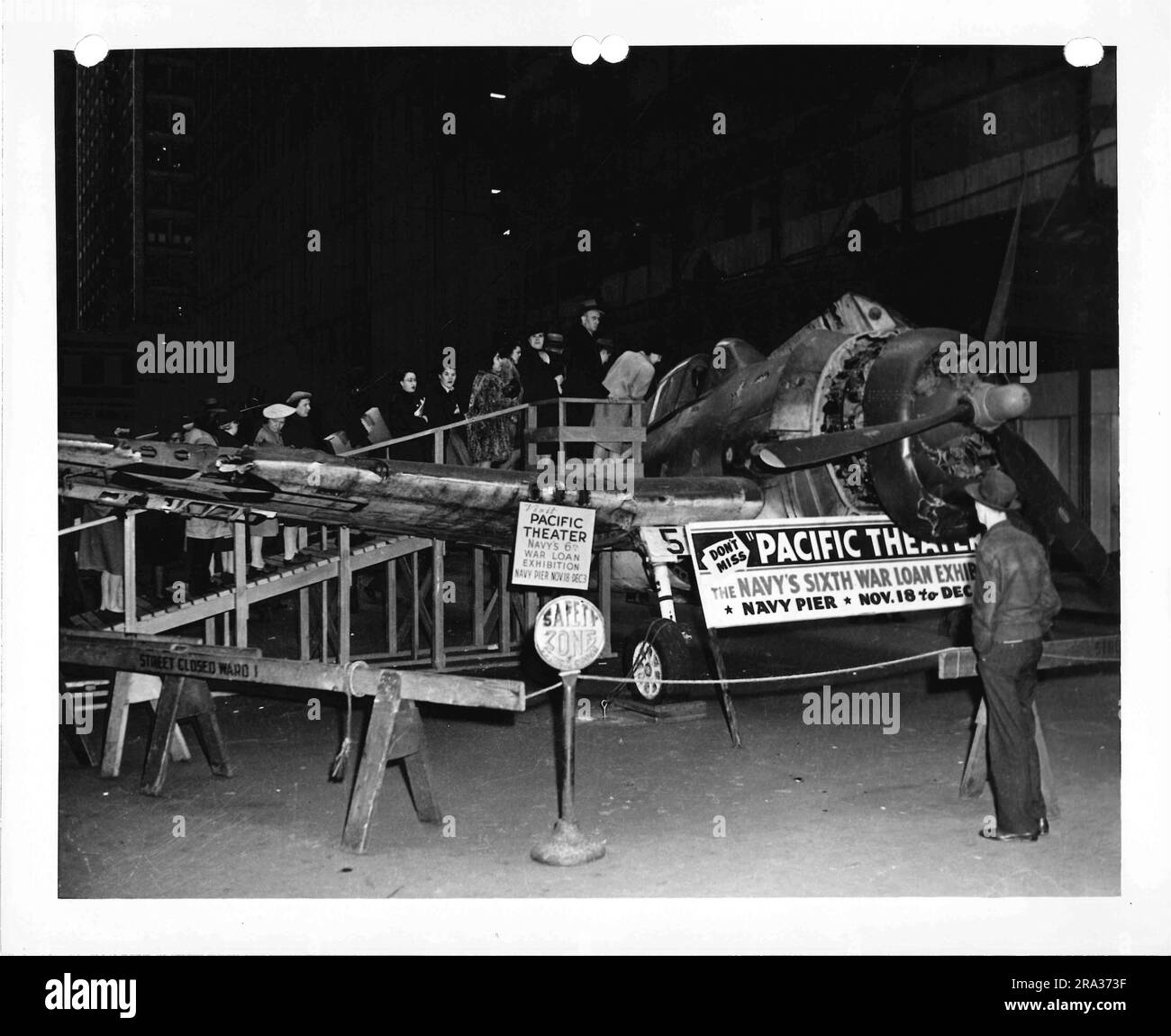 Fotografia di civili che esaminano l'aereo militare con i cartelli che pubblicizzano l'esposizione. Foto Stock