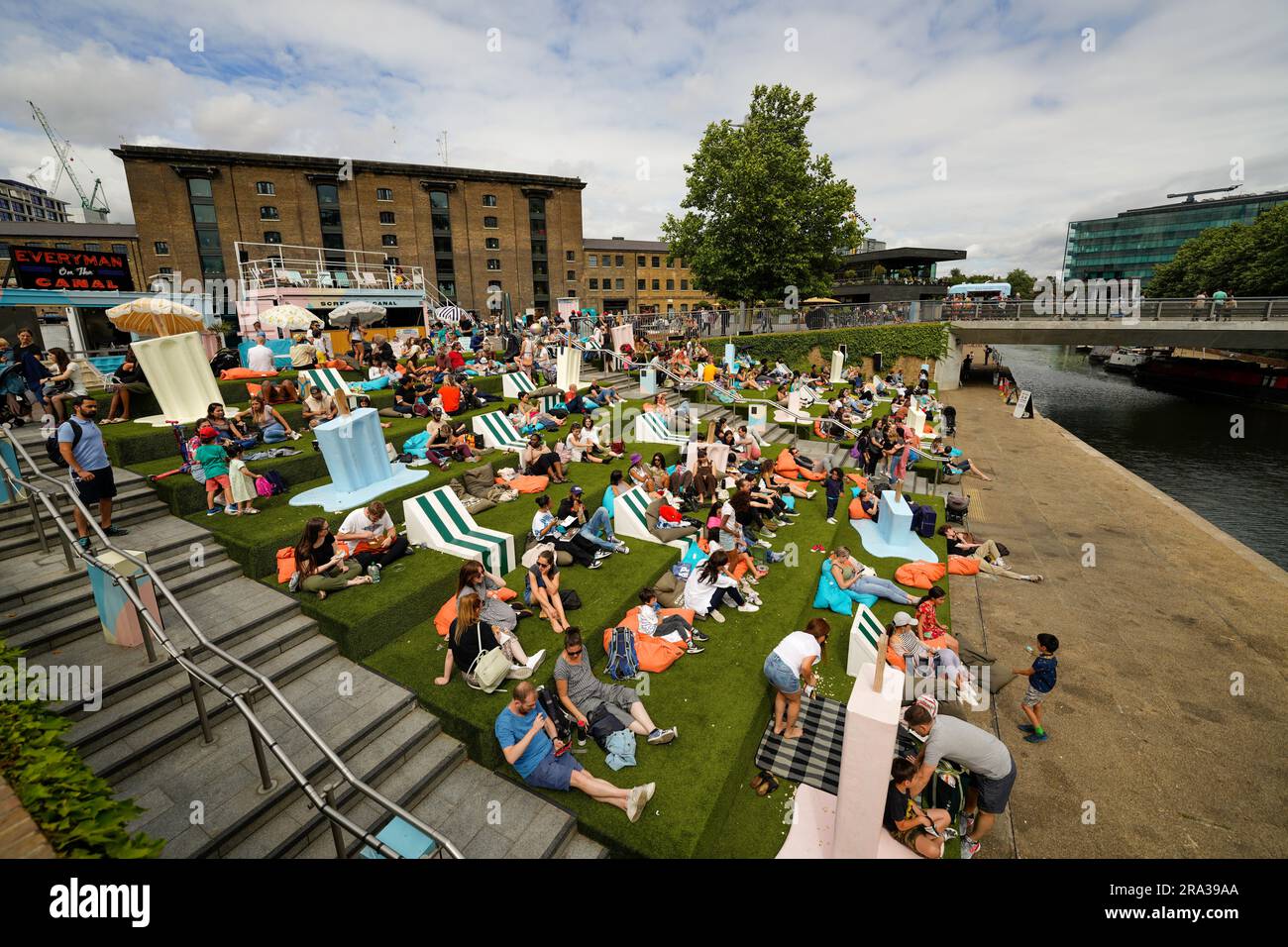 La folla si appresta al cinema all'aperto al Coal Drops Yard di Londra. Originariamente un deposito di carbone, gli edifici storici sono stati convertiti in un mercato Foto Stock