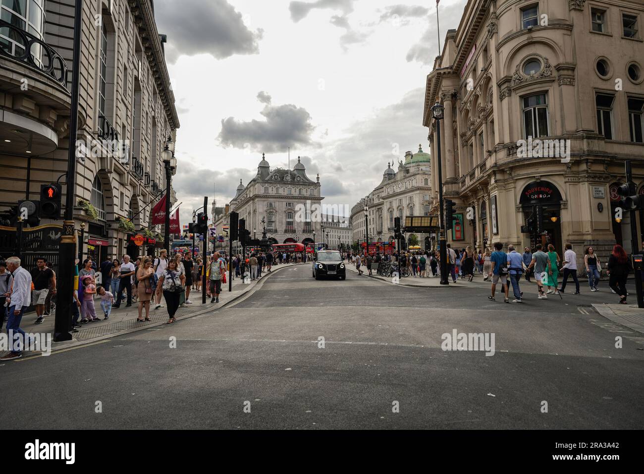 La trafficata strada di Londra a Piccadilly Circus, con l'iconico taxi nero al centro, gli autobus rossi a due piani e la folla di pendolari e turisti sullo sfondo. Foto Stock