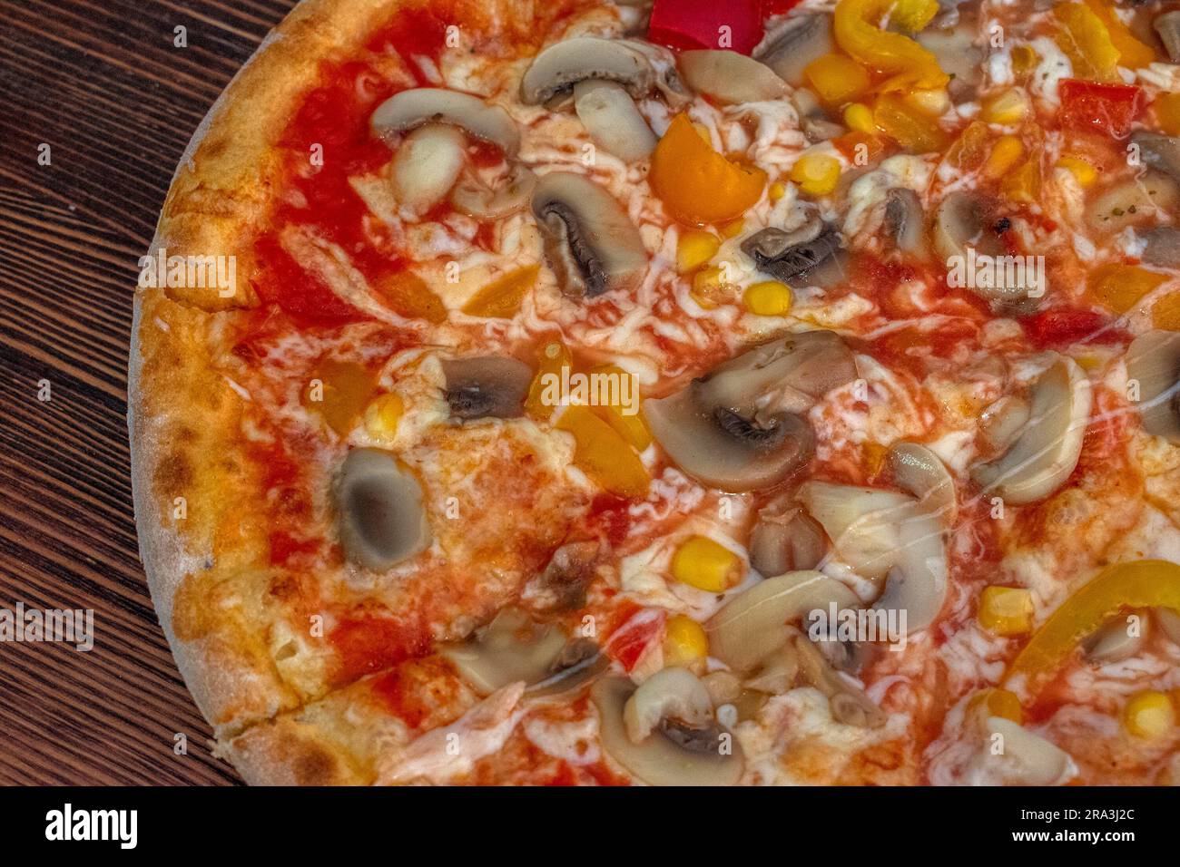 Funghi pizza: Una pizza appetitosa condita con salsa di pomodoro, formaggio fuso, funghi saporiti, peperoni vivaci e mais dolce, tutti serviti su una rus' Foto Stock