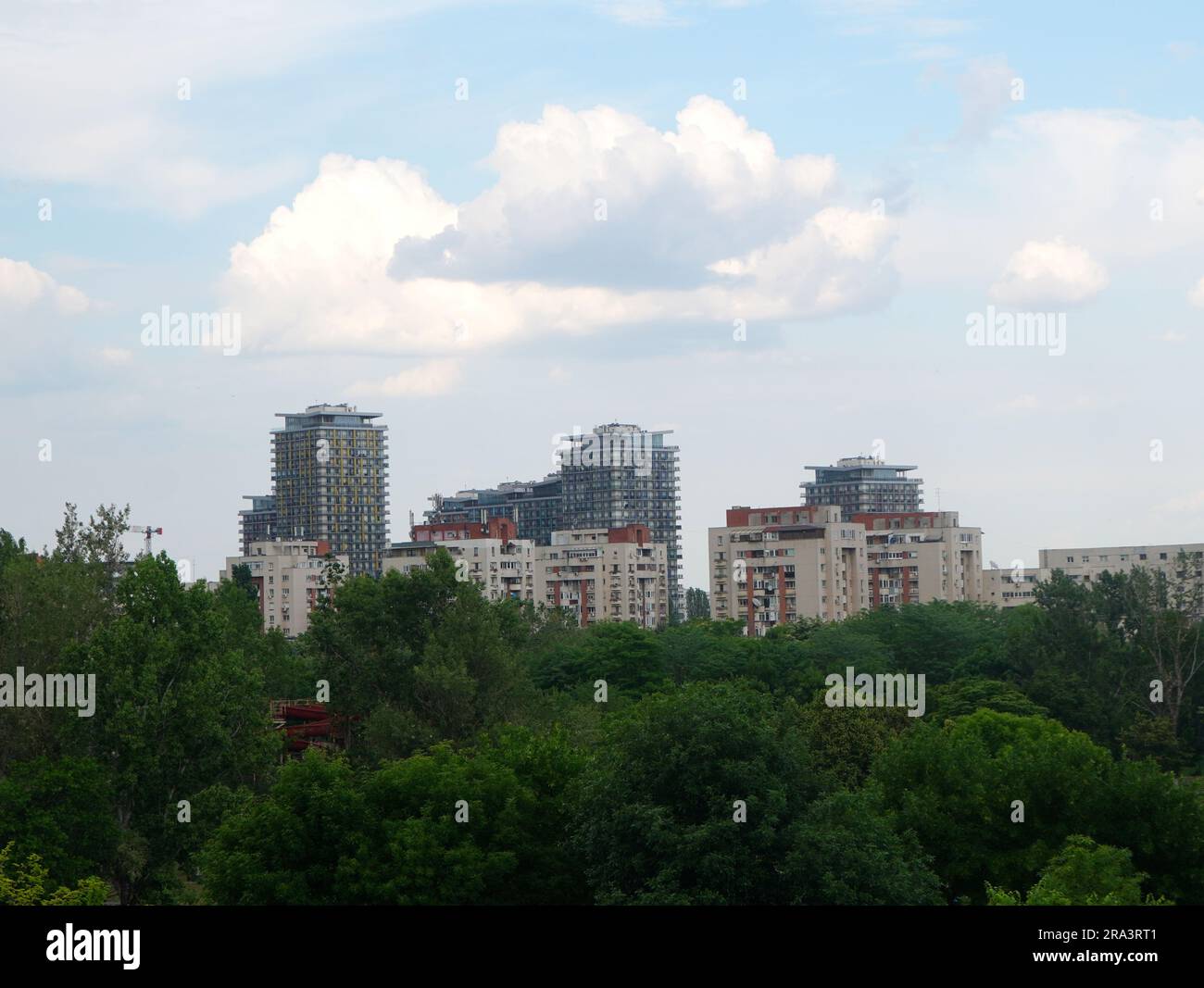 Gruppo di blocchi di appartamenti sul cielo con nuvole bianche, visti su alberi verdi a Bucarest Foto Stock