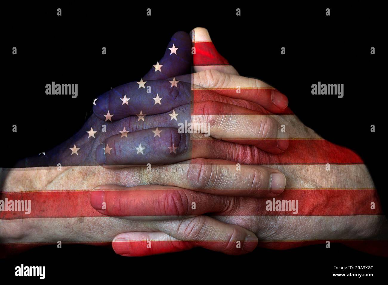 Primo piano delle mani preghiere dell'uomo con la bandiera americana isolata su sfondo nero Foto Stock