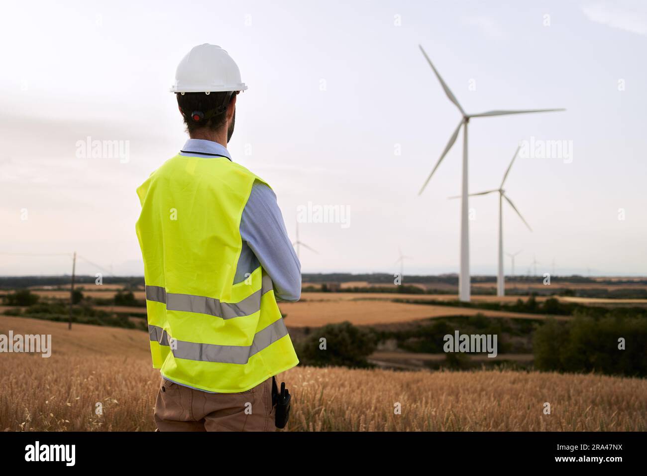 L'ingegnere si è rivolto indietro guardando le installazioni di parchi eolici in campo aperto. Operatore energetico qualificato. Foto Stock