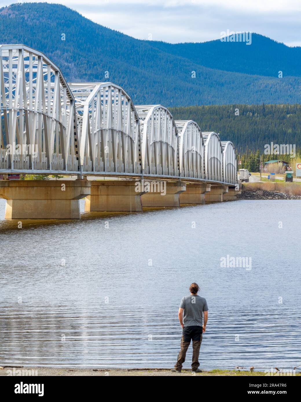 Grande ponte in acciaio costruito dall'uomo che attraversa la baia di Nisutlin nella cittadina di Teslin che scorre verso il fiume Yukon nel Canada settentrionale durante la primavera Foto Stock