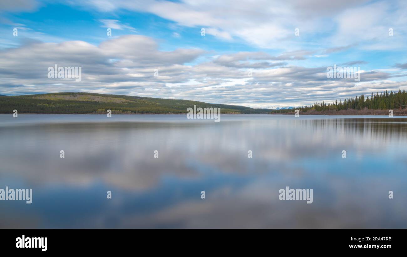 Grande ponte in acciaio costruito dall'uomo che attraversa la baia di Nisutlin nella cittadina di Teslin che scorre verso il fiume Yukon nel Canada settentrionale durante la primavera Foto Stock